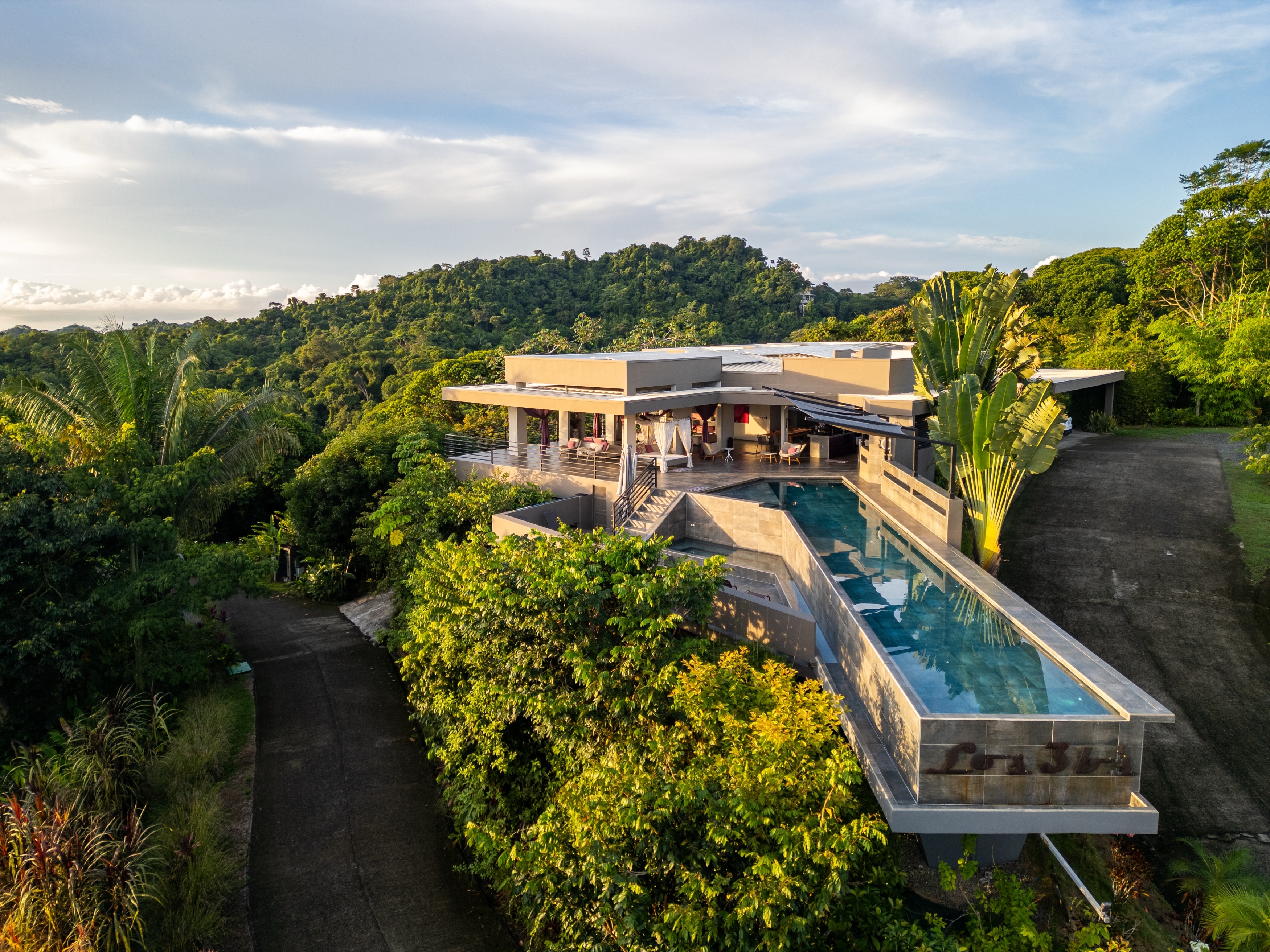 Los 3bs at golden hour — the villa and infinity pool on their ridge above the canopy